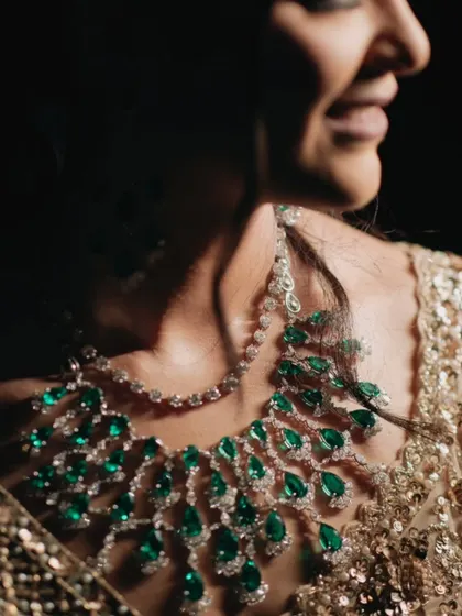 A close-up of the bride's stunning emerald and diamond necklace, a key element of her glamorous look for the sangeet night.