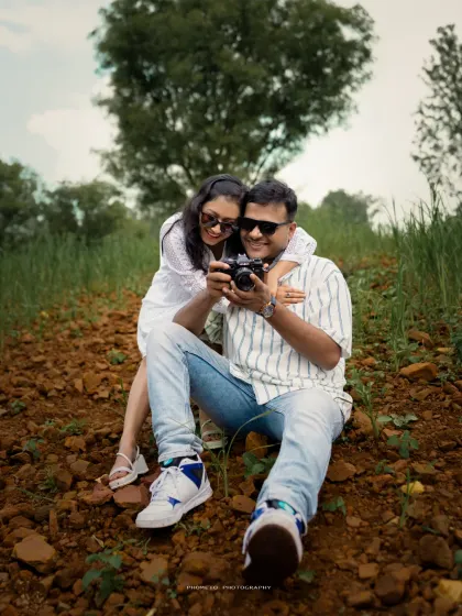 A fun moment during a casual pre-wedding shoot. The couple is looking at their photos on the camera, sharing a laugh.