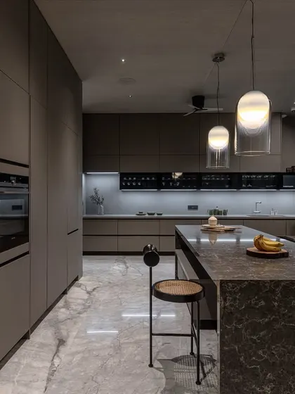 The handleless, floor-to-ceiling cabinets provide immense storage while maintaining a clean, uncluttered look. Integrated shelving offers space for display items.