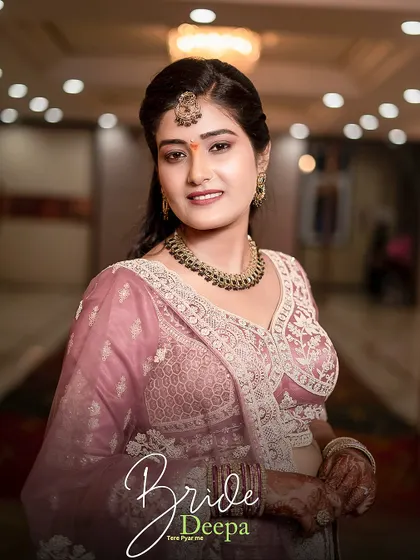 A classic bridal portrait of Deepa, capturing her warm smile and the beautiful details of her necklace and maang tikka.