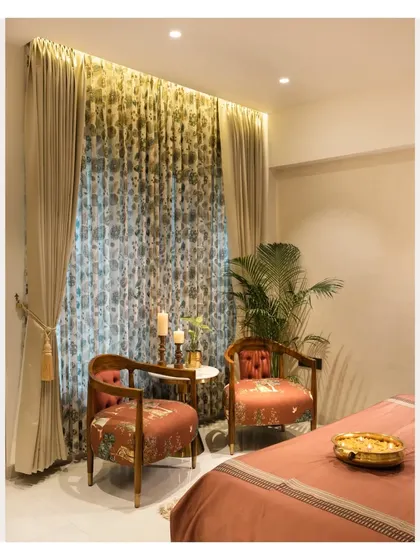 We created a cozy reading corner in this bedroom with a pair of elegant accent chairs and a small side table. The floral curtains and warm lighting make it an ideal spot to unwind.