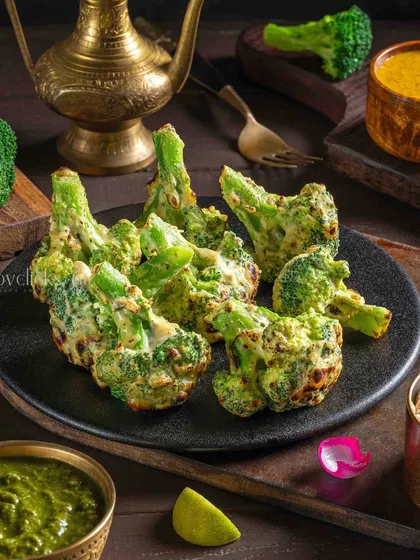 A plate of Malai Broccoli, where florets are marinated in a creamy sauce and grilled, served with mint chutney.