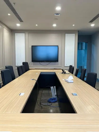 This angle shows the technology wall of the conference room, featuring a central large-screen TV flanked by two vertical whiteboards for brainstorming and presentations.
