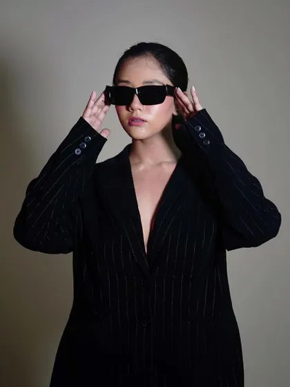 A crisp studio shot focusing on the model's interaction with the sunglasses. This pose is great for e-commerce sites where customers want to see the product from multiple angles.