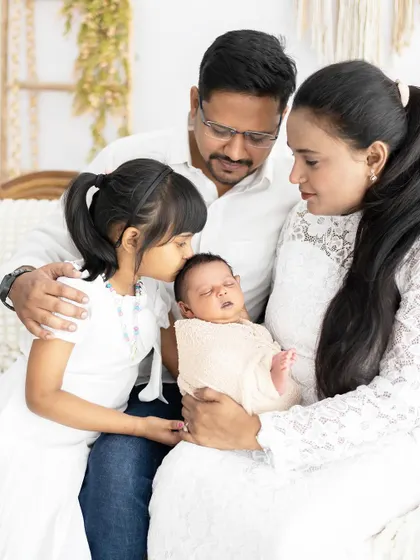 A beautiful family moment, with the big sister giving her new sibling a gentle kiss. These are the memories that families will look back on for a lifetime.