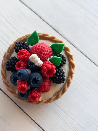 A close-up of a single, incredibly detailed fruit tart candle. It looks good enough to eat!