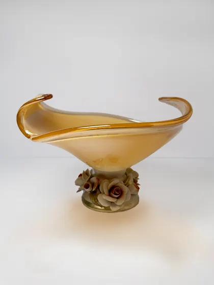 Gracefully perched on a sculpted rose base, this amber-toned Murano vase brings a delicate charm to any space. It is a perfect blend of floral beauty and fine Italian glasswork.