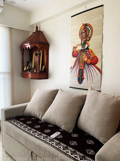 A simple and traditional wooden pooja mandir mounted in the corner of a living room. Paired with a Kathakali painting, it creates a corner that is rich in Indian culture and spirituality.