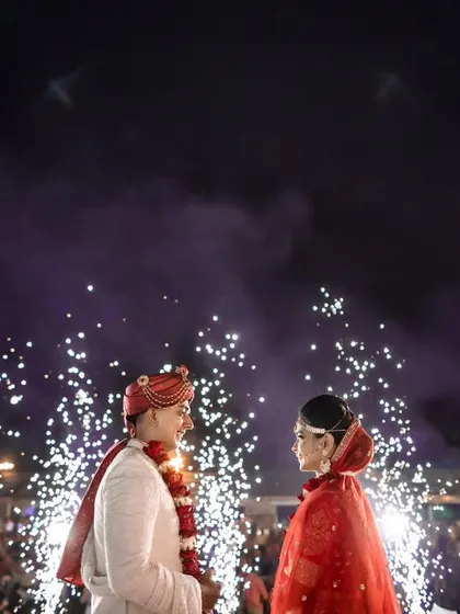 The couple shares a look as fireworks light up the night sky behind them. This is a classic, grand finale shot that every couple dreams of.