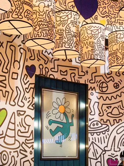 The pre-dining room at 'The Glitch Pop' was a tribute to Keith Haring's unique doodle style. The walls were covered in black-and-white art, with custom lampshades and framed prints adding pops of color.