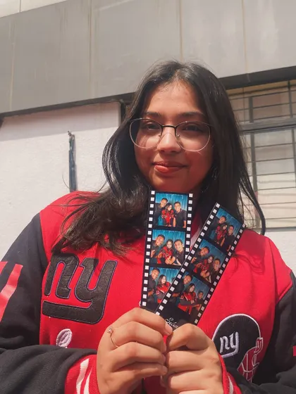 A student proudly holding up her filmstrip-style prints.