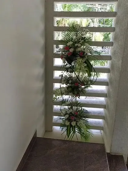 A creative way to decorate architectural details in a home. Here, we've placed cascading floral arrangements within a slatted window feature, adding a touch of elegance to an unexpected corner.