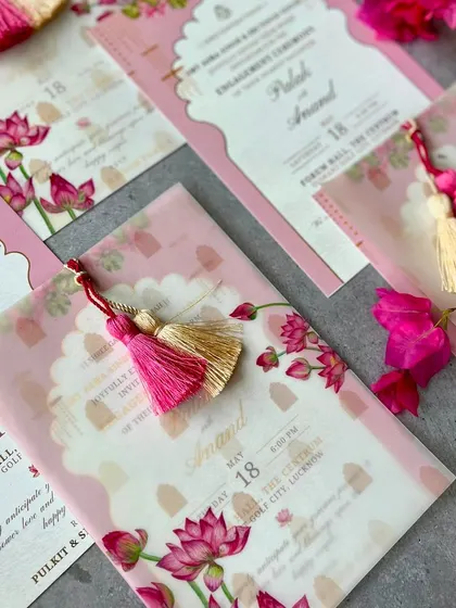 A close-up of the layered lotus invitations, highlighting the delicate tassels and the translucent effect of the vellum paper.