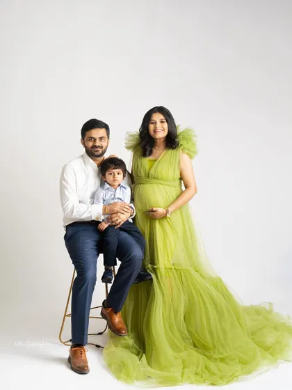 A stunning maternity portrait of a family of three, soon to be four. The mother looks radiant in her green gown, full of anticipation and joy.