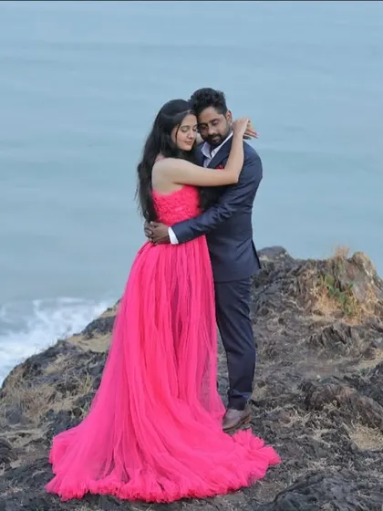 An epic pre-wedding shot on a cliffside. The vibrant pink gown provides a stunning pop of color against the blue ocean and sky.