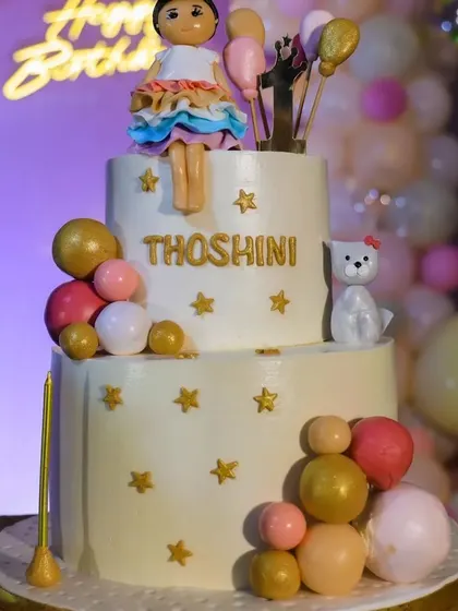We arranged this lovely two-tier cake for Thoshini's party. The design included a cute doll topper, stars, and decorative spheres that perfectly matched the pastel theme of the event.