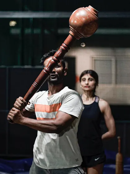 A coach guiding a member through a Gada swing. It's about learning the technique and respecting the weight. This is where strength and skill come together.