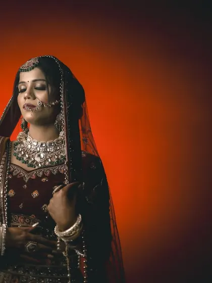 A dramatic bridal portrait with a gradient red background. The lighting creates a moody, cinematic feel that is part of our signature style.