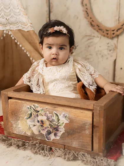 A peek-a-boo moment. This 5-month-old baby, sitting in a rustic wooden box, has the most curious and engaging expression.