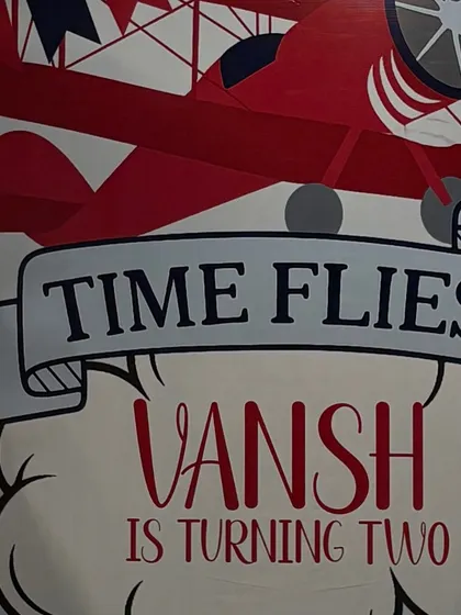 The custom-designed "Time Flies" backdrop, featuring vintage airplane graphics and personalized text for the birthday boy.