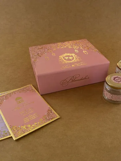 A lovely pastel pink box with gold foil detailing and a custom crest. This set includes matching inserts and two small jars for sweets or other favors.