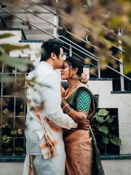 A groom tenderly kisses his bride's forehead, a classic and timeless romantic gesture captured beautifully.