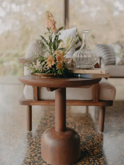 A close-up of the carefully chosen decor, including a wooden side table and a beautiful floral arrangement, reflecting our commitment to natural elegance.