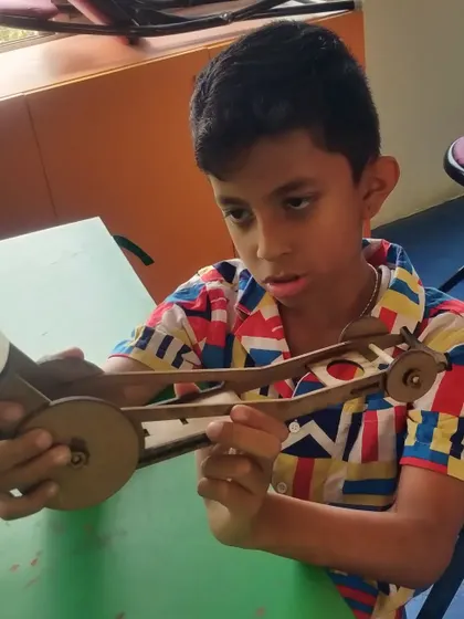 A student proudly displays the rubber-powered car he assembled. This project teaches the basics of potential and kinetic energy.