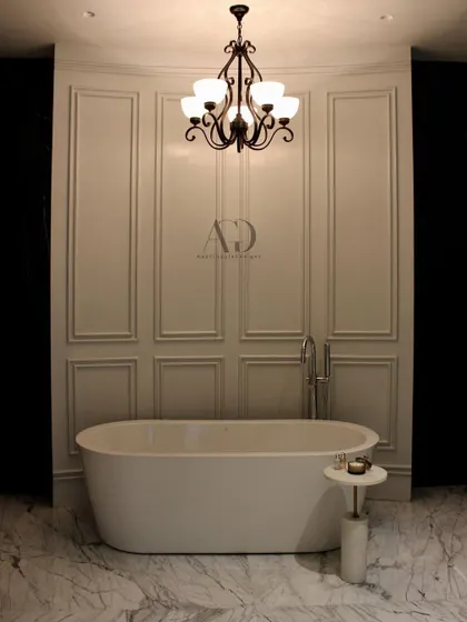 A minimalist approach to classic design. This bathroom features a simple, elegant freestanding tub set against a backdrop of clean, white paneled walls and a classic chandelier, proving that luxury can be understated.
