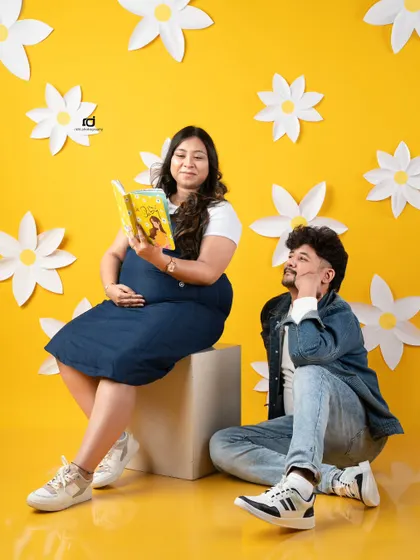 Reading stories to the little one already. This fun and creative shot with a bright yellow background and paper flowers shows the couple's playful personality.