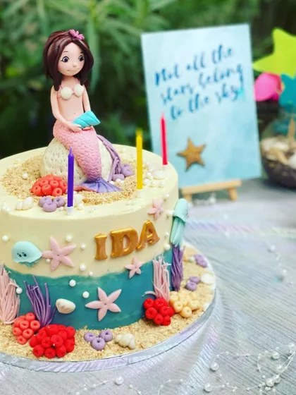 A close-up of the beautiful, custom-made mermaid cake. I work with talented bakers to ensure even the treats match the party's theme perfectly, complete with a mermaid figure, edible sand, and sea creatures.