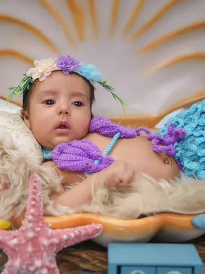 Our little mermaid looking curious and alert. The vibrant colors of her outfit and the seashell prop create a magical underwater world.