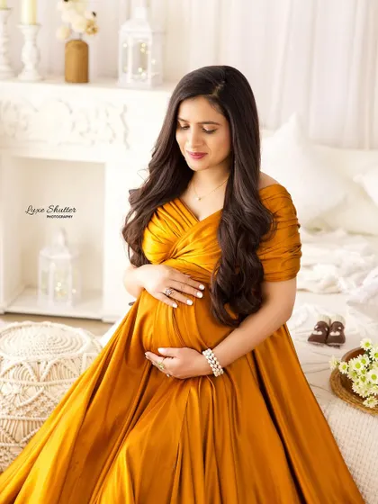 A close-up shot focusing on the tender moment as the mom-to-be cradles her bump in a beautiful yellow gown.
