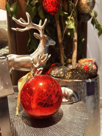 A close-up of our Christmas decor, featuring a silver reindeer figurine and a bright red bauble. It's these little details that create the magic.