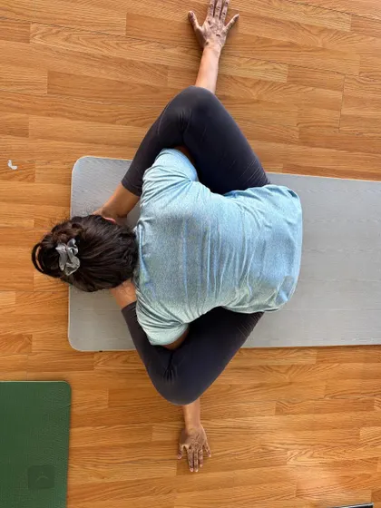 A beautiful overhead shot of a student in Gomukhasana (Cow Face Pose) forward bend.