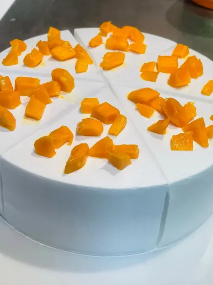 Our minimalist Mango Cake, topped with fresh mango chunks and pre-sliced for easy serving.