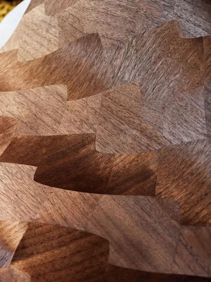 A close-up of our wood marquetry wallpaper, showcasing the grain and texture of the paper-thin slices of paulownia. Light and shadow weave an evocative narrative across the undulating surface.