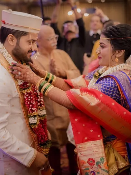 The bride places the varmala over the groom, a significant and joyous moment in the wedding ceremony, surrounded by family.