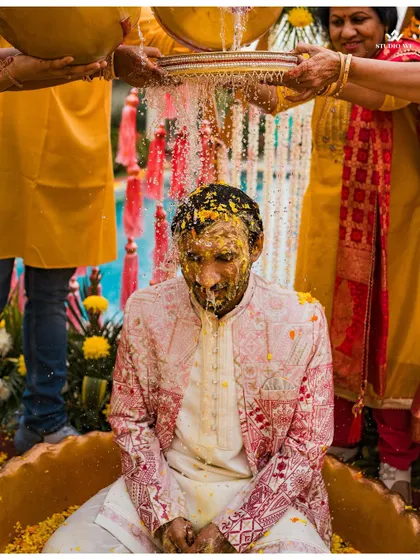 A close-up of the groom during his Haldi ceremony, his face covered in turmeric as he is blessed by family.