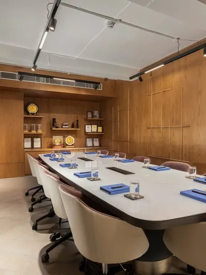 The conference room at the award-winning SIRCA HQ project. The space is paneled in warm wood, with integrated shelving for awards, creating a sophisticated and professional environment.