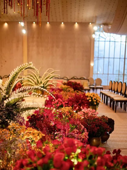 A field of flowers in rich, warm tones lines the aisle, leading the eye towards the main ceremony space.