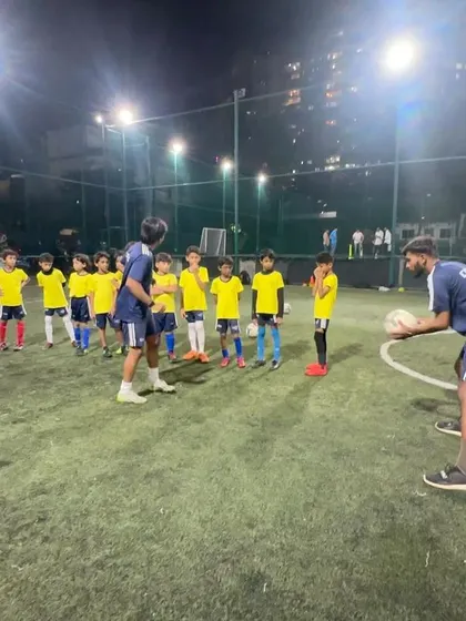 A coach prepares to toss the ball for a volley drill, ensuring the players are ready and in position.