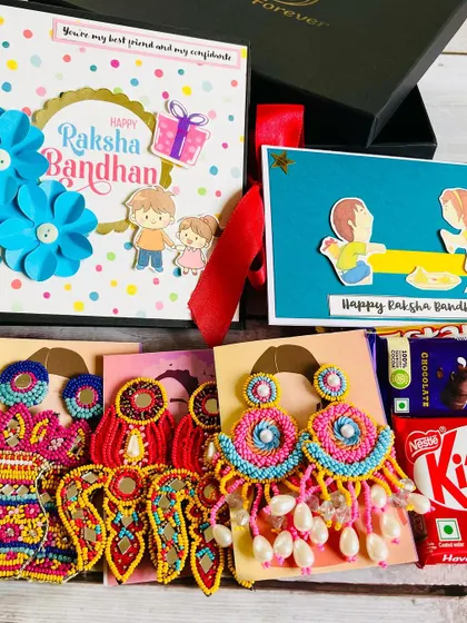 For the sister with a bold sense of style, we offer a wide range of handmade earrings to include in our Rakhi hampers. This flat-lay shows the variety you can choose from to complement the memory album.