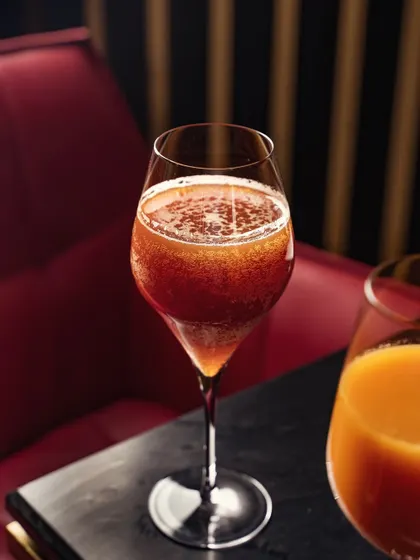 Another view of the sophisticated beverage, this time set against a red booth. The composition uses the background to add a pop of color and enhance the upscale atmosphere.