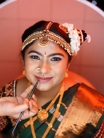Using a precise lip brush to apply the perfect shade of lipstick. This technique ensures a clean, sharp line and long-lasting color for the bride.