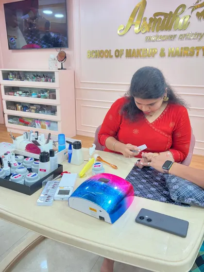A student practicing on a model, using a UV lamp to cure the gel polish.