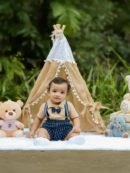 A classic outdoor first birthday setup with a teddy bear picnic theme. The natural greenery provides a beautiful, soft background.
