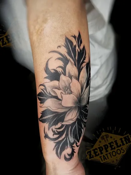 The finished floral cover-up tattoo, seen here in high detail. The combination of soft grey shading on the flower and solid black on the leaves creates depth and ensures the old tattoo is gone for good.