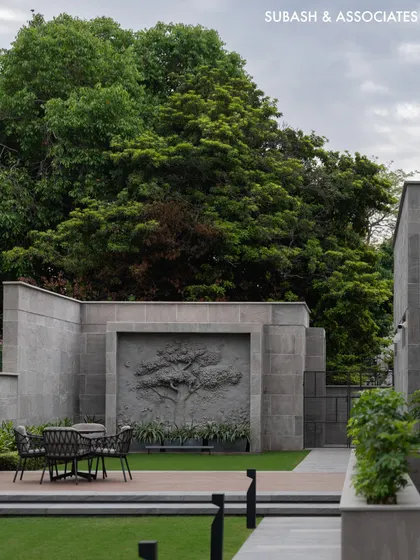 The side lawn features a custom stone relief sculpture of a tree, creating a serene focal point for this outdoor seating area.