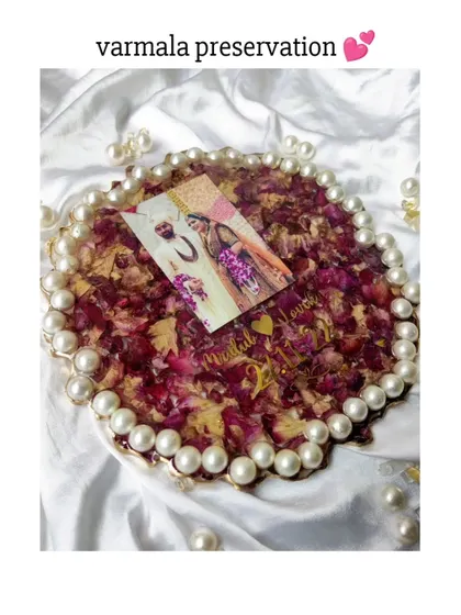 A full view of a round resin frame with a pearl border, filled with preserved varmala petals. This piece is ready to be displayed and cherished for years to come.